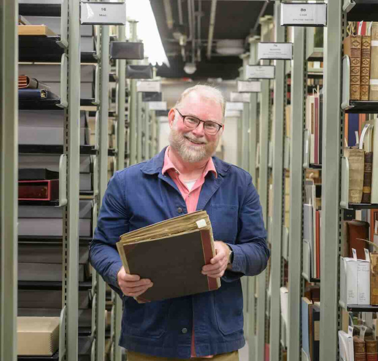 Eric Johnson-DeBaufre, Rare Books and Special Collections Librarian for the Watkinson Library at Trinity College, poses with a collection of scraps from the archives containing a page from an Aelius Donatus.